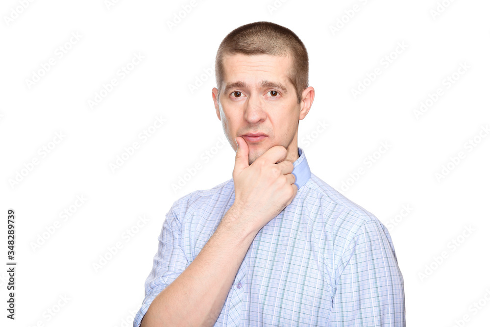 incredulous suspicious man in a classic blue shirt; holds his hand at the chin in doubt and reflection; look into the camera. Isolated incredulous suspicious man in a classic blue shirt; holds his hand at the chin in doubt and reflection; look into the camera. Isolated