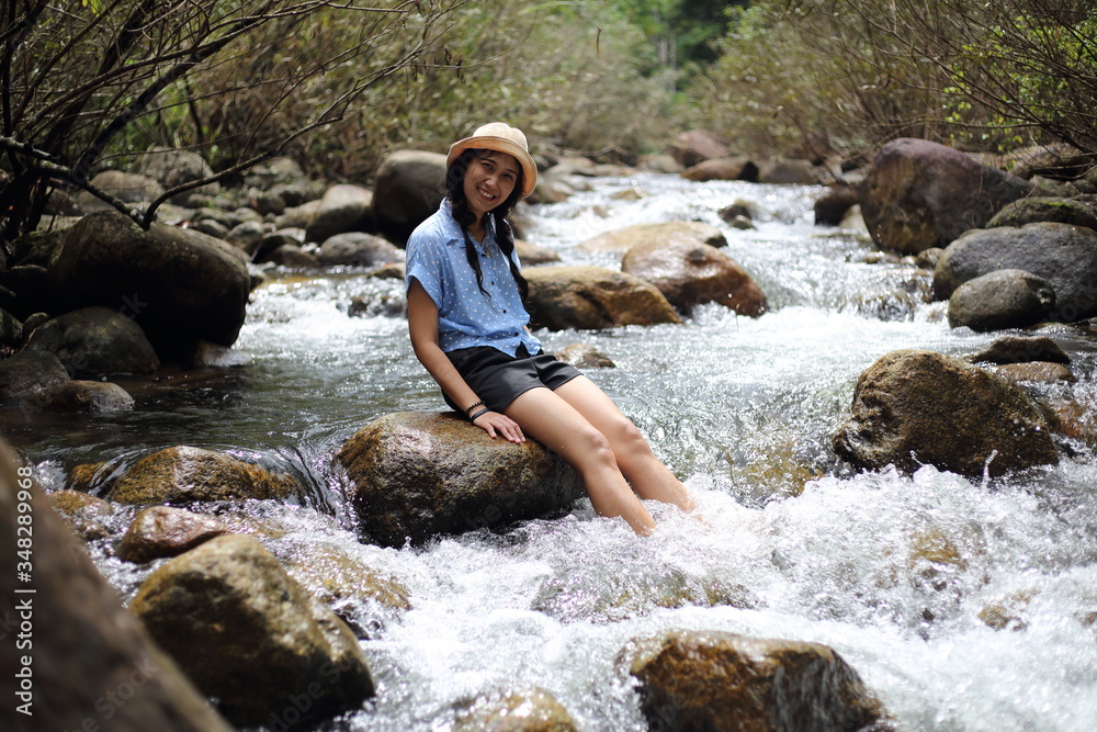 Woman sitting on a rock at Trok Nong Waterfall in Chanthaburi, Thailand Woman sitting on a rock at Trok Nong Waterfall in Chanthaburi, Thailand