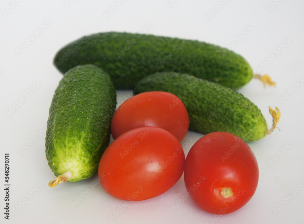 green cucumbers and red tomatoes close up on a white background green cucumbers and red tomatoes close up on a white background