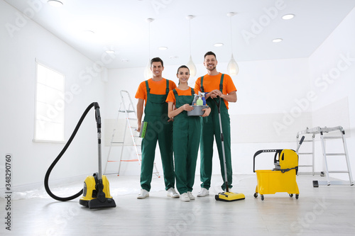 Team of professional janitors with cleaning supplies indoors