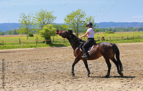 Girl is  riding wild horse in the riding school © Geza Farkas