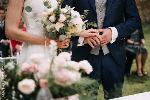 photo of a bride with bouquet and the groom in the garden