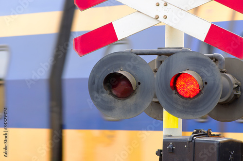 Fotografie Red stop signal at a level crossing with a train in the background