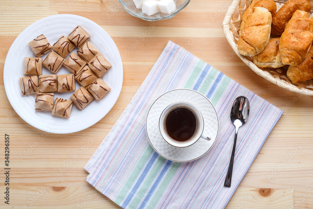 Cup of coffee on napkins on a wooden table with croissants and waffles. Cup of coffee on napkins on a wooden table with croissants and waffles.