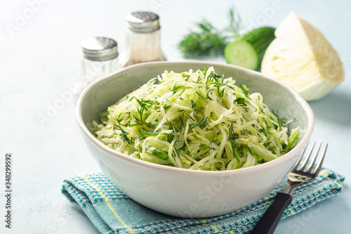 Fresh cabbage and cucumber salad with dill in bowl on concrete background. Coleslaw.