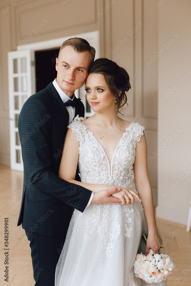 The bride and groom, European appearance. Hold hands, smile and hug. Wedding couple. Waist-high portrait
indoors or photo studio.