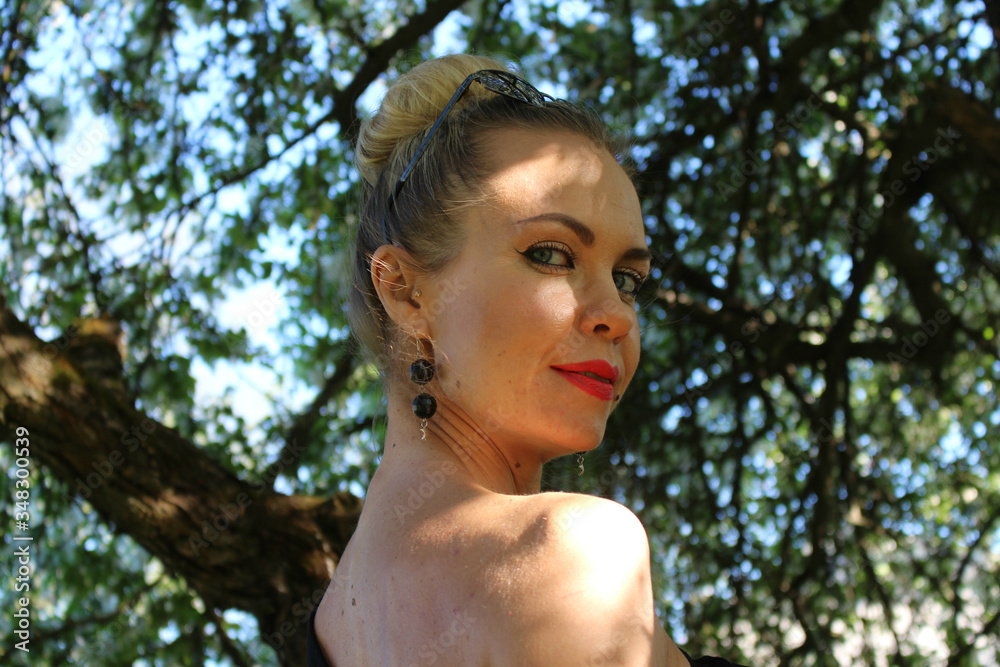 Portrait of a beautiful woman standing half a turn with shadows from tree branches on her face. Portrait of a beautiful woman standing half a turn with shadows from tree branches on her face.