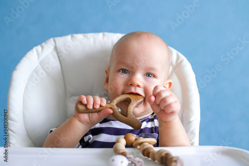eco wood toys. baby game. Little clever caucasian child playing natural toys on highchair. games for early development. Toy in kids mouth photo