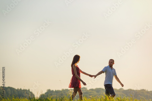 Happy couple is walking together in green field. summer. meadow,