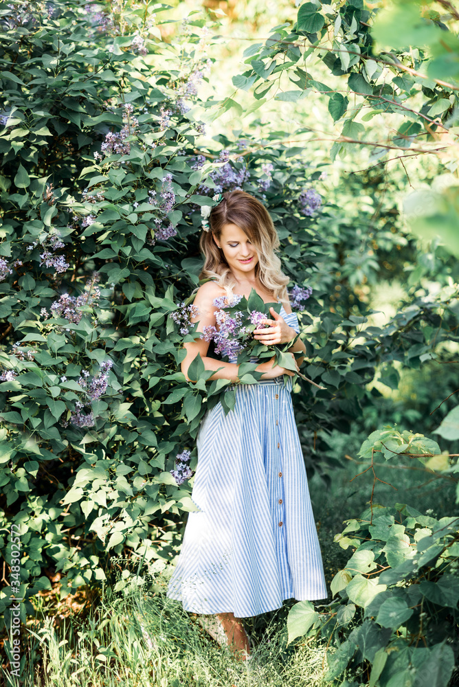 A beautiful happy young woman enjoys the smell in a blooming spring Lilac garden. Happy beautiful woman enjoying nature. A trendy modern look . A beautiful happy young woman enjoys the smell in a blooming spring Lilac garden. Happy beautiful woman enjoying nature. A trendy modern look .