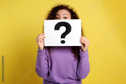 African-American woman with question mark sign on yellow background photo