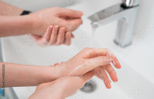 Family washing hands under water tap at home. Coronavirus protection concept.