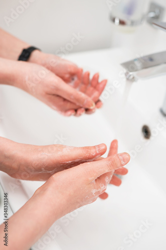 Family washing hands under water tap at home. Coronavirus protection concept. © M-Production