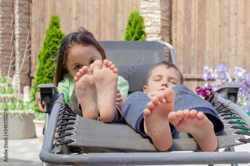children's bare feet on a chaise longue. resting boy and girl in the sun. The concept of relaxation.