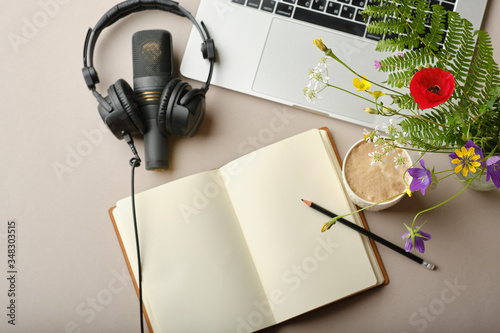.Top view Flowers, Microphone for podcasts  and black studio headphones on brown background with coffee and laptop, learning online education concept...