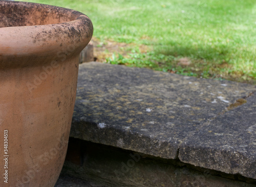 Edge of terracotta pot beside step in green lawned garden