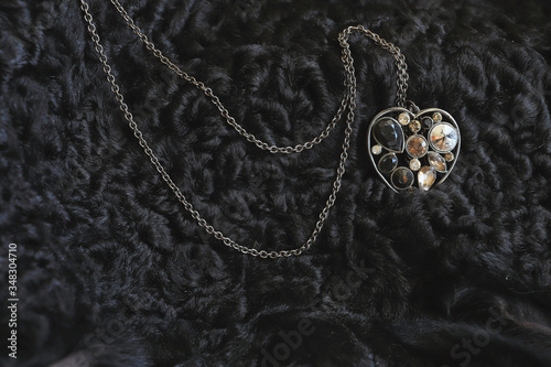 bijouterie. the necklace lies on a black sheep skin. contrast. the stones shimmer from the natural sun color.