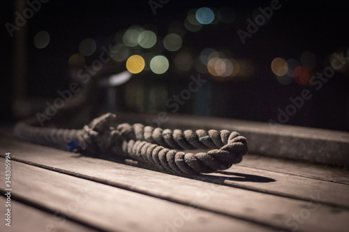 Rope noose on a wooden jetty at night with soft city lights in the background