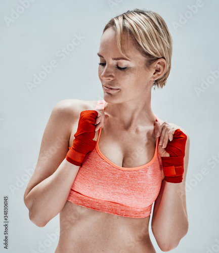 Photo of a beautiful female model posing while preparing her hands for doing martial arts wearing sporty underwear and kumpur tapes photo