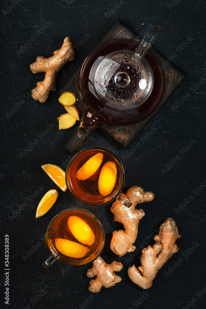 Healing black herbal tea with ginger, honey, lemon and sage. Immune booster drink in glass cup on black kitchen table background with copy space. Top view Healing black herbal tea with ginger, honey, lemon and sage. Immune booster drink in glass cup on black kitchen table background with copy space. Top view