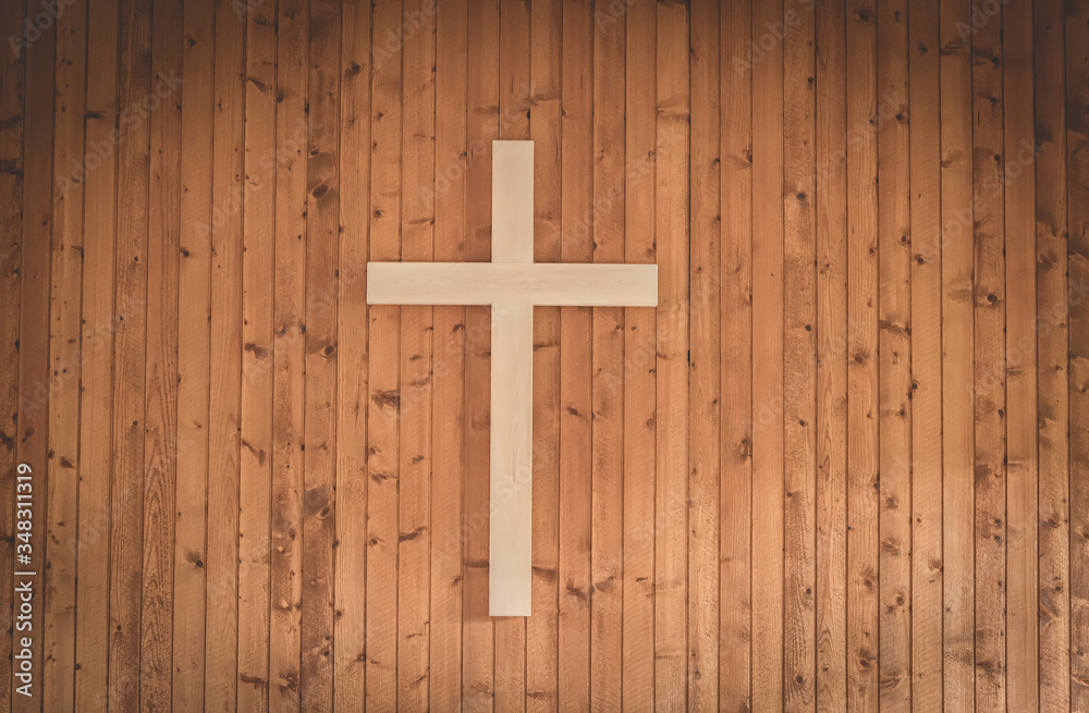 A christian cross in wood on a wall inside a church