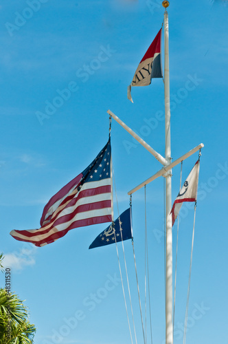 Front view, far distance of a flag pole with an American flag, yacht club flag and a Marco Island on a sunny, spring day