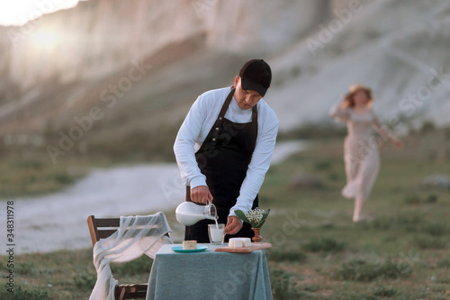 A young man in nature pours milk from a jug.