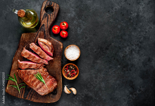 grilled beef steak with spices on a cutting board on a stone background