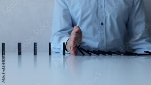 Man stops of queued up falling dominos. Social distancing and saving from spreading virus, concept.