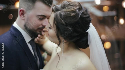 Happy bride and groom in wedding dresses ride in the hotel elevator, hug and kiss. Wife with bouquet of flowers and wedding dress and bearded husband in a suit caress each other in a modern elevator. photo