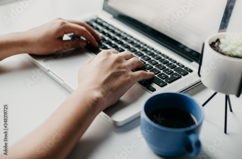 woman hands working on a laptop with a cup of coffee