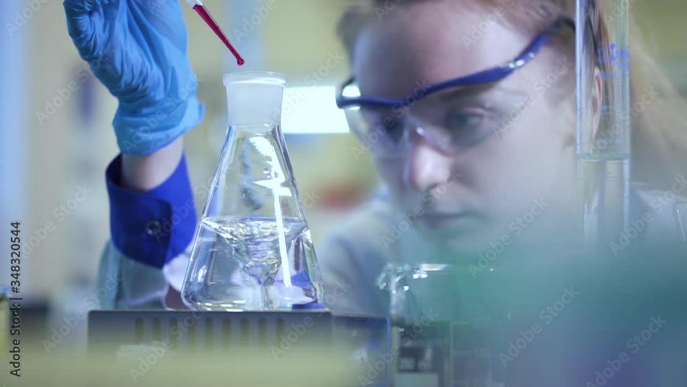 woman scientist in the laboratory mixing chemical reagent yellow liquid in stirring beaker Spbd. female doctor watching reaction in flask. concept analyzing, check, research. woman scientist in the laboratory mixing chemical reagent yellow liquid in stirring beaker Spbd. female doctor watching reaction in flask. concept analyzing, check, research.
