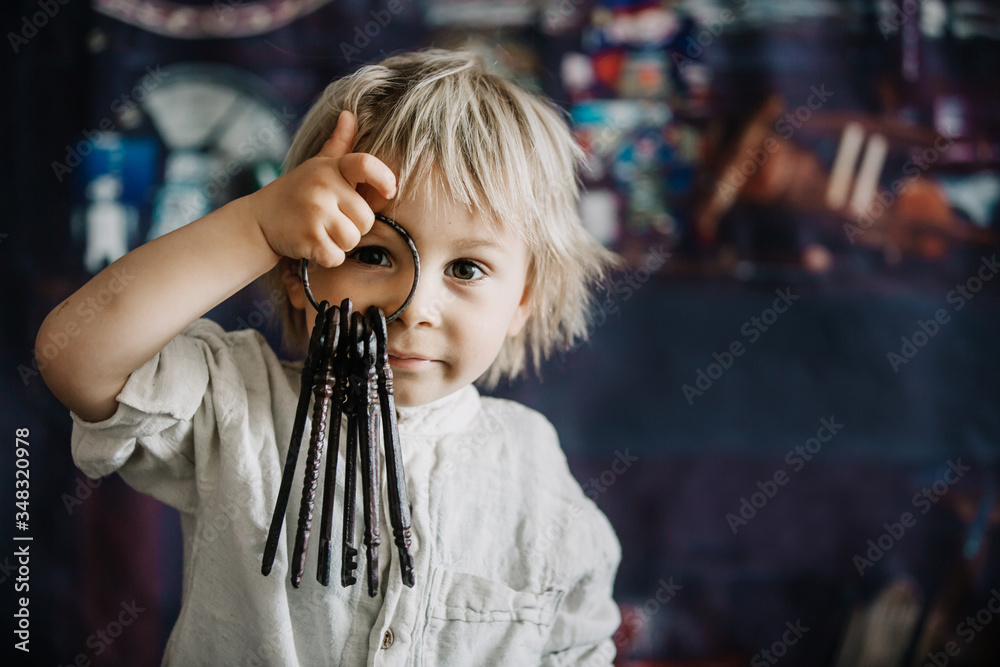 Toddler child, holding old vintage keys and bouquet of wild flowers in vase