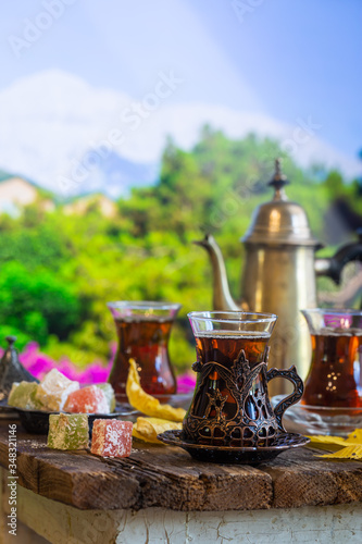 Glass Cup of turkish tea served in traditional style with summer outdore view