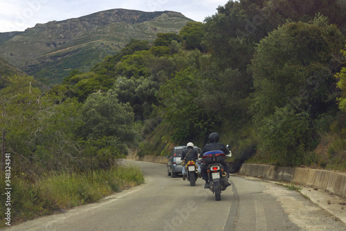 Two motorbikes following car before turning road in mountain area. © Irinka