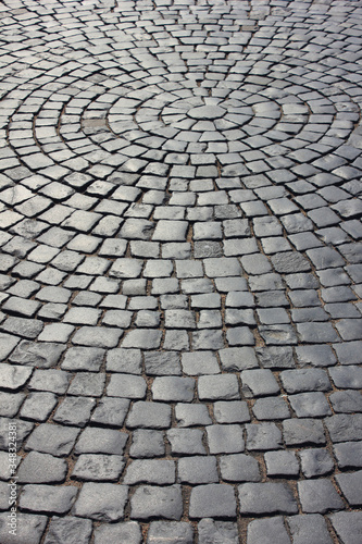 Brick cobblestone street background with rocky pavement pattern. Empty grey stone paved pattern, old town ancient street detail, abstract cobblestone pavement perspective on sunny day with no people
