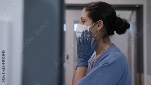 Nurse fixing surgical mask in infection room and preparing for treating corona virus photo