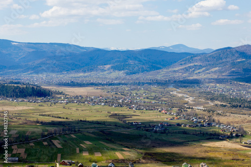 View of the Carpathian Mountains landscape in cloudy summer day. Mountain peaks, forests, fields and meadows, beautiful natural landscape