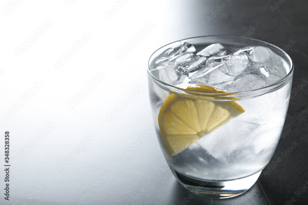 Water with ice cubes and lemon on grey table, closeup. Space for text