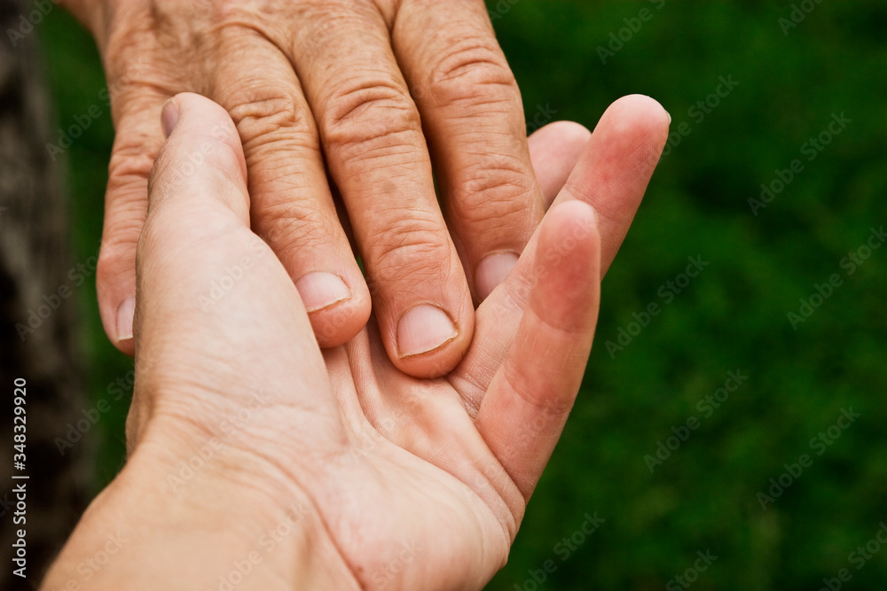 The old hand touches the young hand close-up. Young hands hold grandmother's old wrinkled hands. Good grandmother hands in the palms of children close-up. Caring for the elderly. The old hand touches the young hand close-up. Young hands hold grandmother's old wrinkled hands. Good grandmother hands in the palms of children close-up. Caring for the elderly.