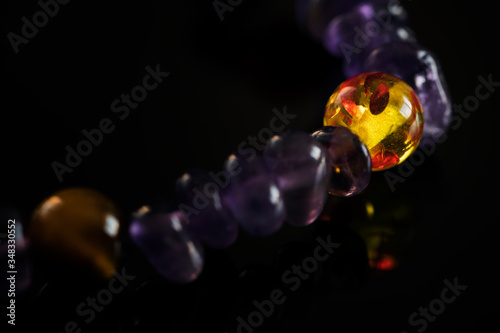 Balls of semiprecious stones on a leash with amethysts on a hand on a black background.