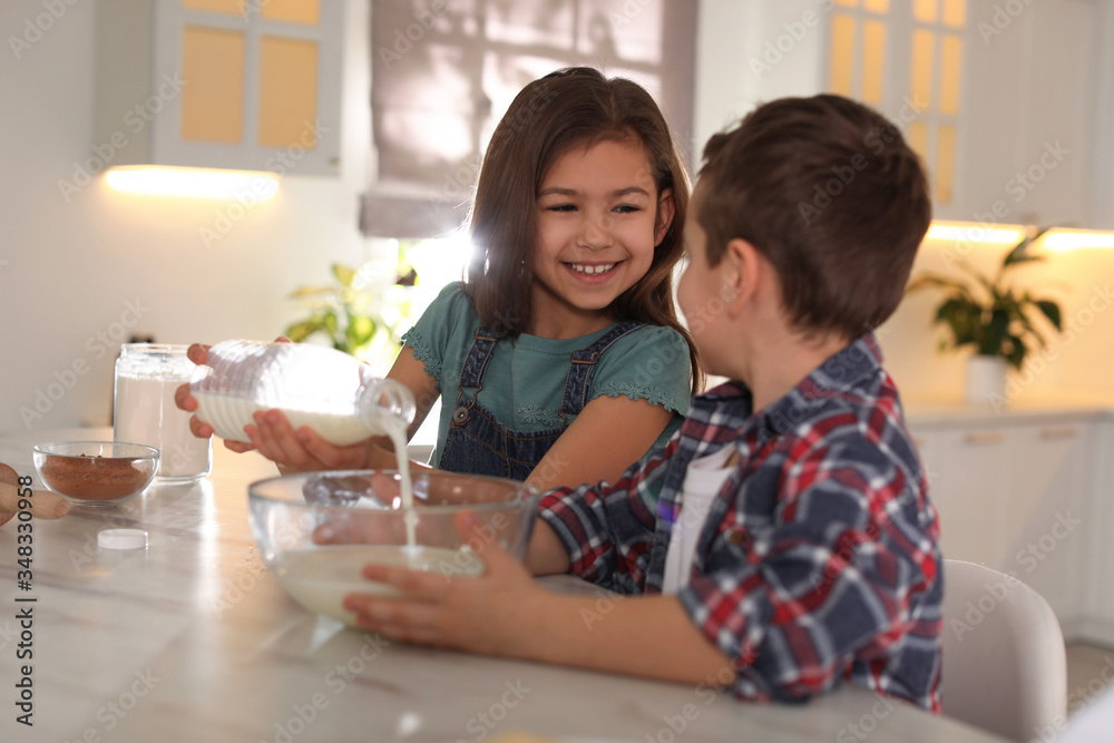 Cute little children cooking dough in kitchen at home Cute little children cooking dough in kitchen at home
