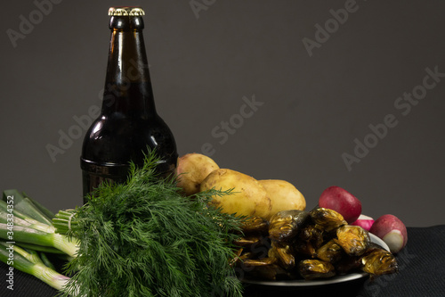 A bottle of dark beer and a plate of fish. On a dark background.