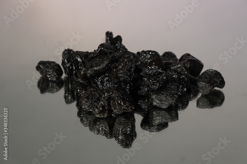 prunes on the mirror surface on agray background photo