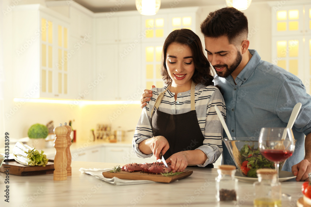 Lovely young couple cooking meat together in kitchen Lovely young couple cooking meat together in kitchen