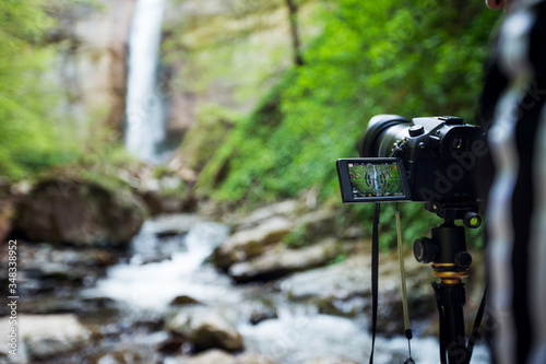 Camera on the tripod filming waterfall