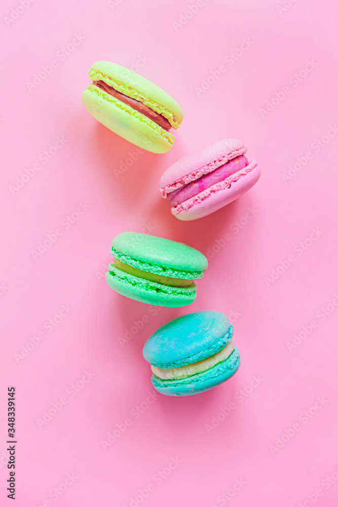 Obraz premium Sweet almond colorful pink blue yellow green macaron or macaroon dessert cake isolated on trendy pink pastel background. French sweet cookie. Minimal food bakery concept. Flat lay top view, copy space