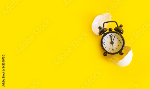 Black clock on a yellow background in an egg shell