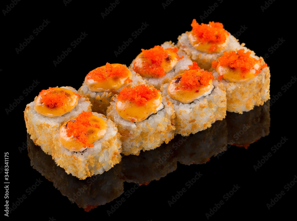 Fried Sushi Uramaki roll with sauce and tobiko caviar on top isolated on black background with reflection Fried Sushi Uramaki roll with sauce and tobiko caviar on top isolated on black background with reflection