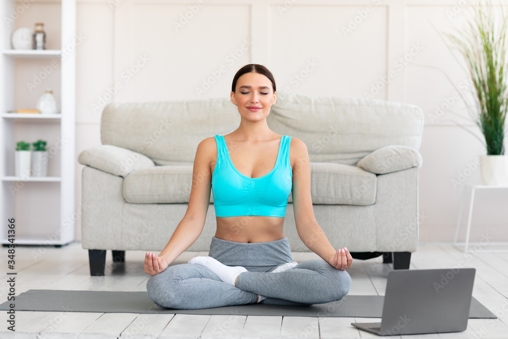 Girl Meditating At Laptop Sitting In Lotus Position At Home Girl Meditating At Laptop Sitting In Lotus Position At Home